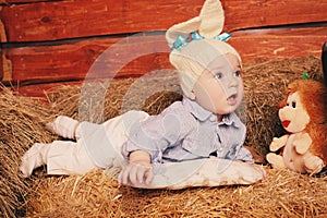 Cute little baby boy in funny bunny hat lying on straw