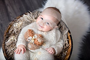 Cute little baby boy with handmade knitted cloths, playing with