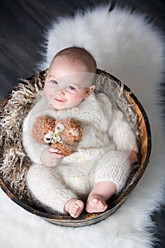 Cute little baby boy with handmade knitted cloths, playing with