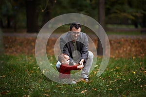 Cute little baby boy and his father. Dad and son having fun on autumn day in city park