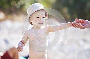 Cute little baby boy holding mom's hand while walking