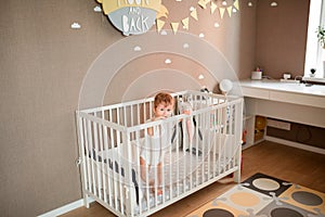 Cute little baby boy looking out of his bed