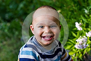 Cute little baby boy outdoors. Happy smiling baby at green garden