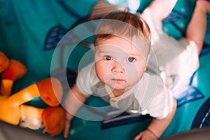 Cute little baby boy playing in colorful playpen, indoors. Beautiful child having fun at nursery