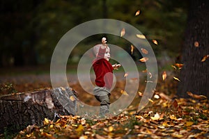 Cute little baby boy playing and having fun in autumn park with yellow leaves