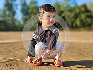 Cute little baby boy playing with rope in a park and smiling. Child crawling in a public park and looking up with happy face.