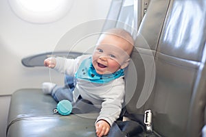 Cute little baby boy, playing with toys on board of aircraft