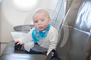 Cute little baby boy, playing with toys on board of aircraft