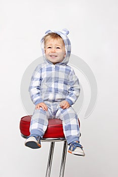 Cute little baby boy sitting on red chair and smiling.