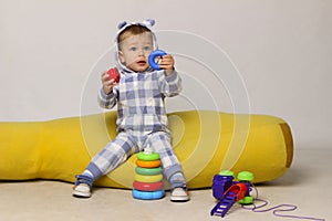 Cute Little Baby Boy Sitting On a Yellow Bean Bag Chair and Playing Toys.