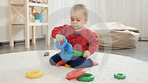 Cute little baby boy trying assembling colorful toy pyramid tower. Baby development, child playing games, education and learning