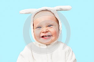 Cute little baby in bunny costume is smiling on a blue background. Easter baby rabbit