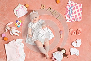 Cute little baby with clothing and accessories on color blanket