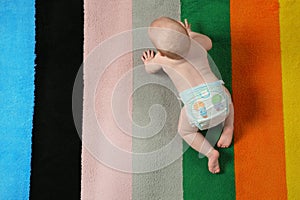 Cute little baby crawling on colorful carpet indoors with space for text