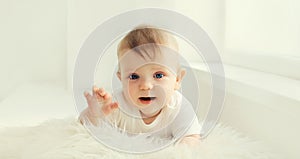 Cute little baby crawling on the floor in white room at home