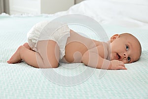 Cute little baby in diaper on bed at home