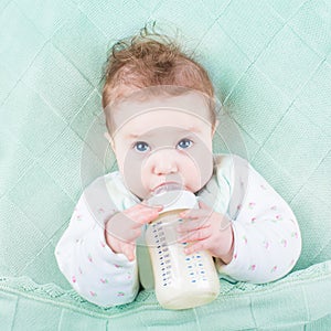 Cute little baby drinking milk formula out of bottle