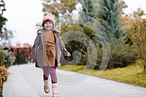 Cute little baby girl 4-5 year old wear casual clothes walk in park. Looking at camera. Springtime.