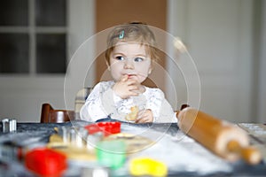 Cute little baby girl baking gingerbread Christmas cookies at home.