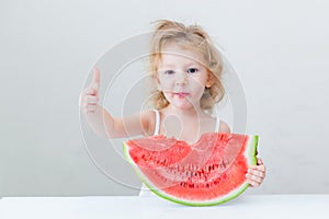 Cute little baby girl eating watermelon slice on light background