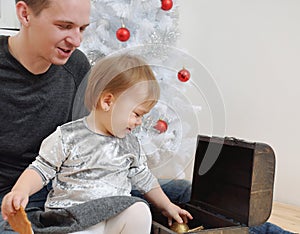 Cute little baby girl and her dady having fun with Christmas toy