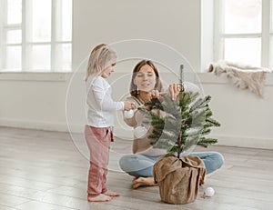 Cute little baby girl with her mom play in a spacious bright minimalistic children`s room.