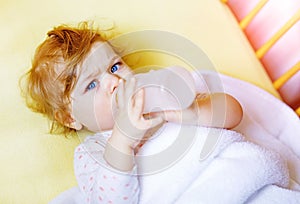 Cute little baby girl holding bottle with formula mild and drinking. Child in baby cot bed before sleeping