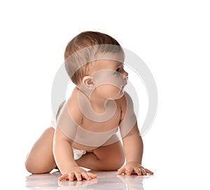 Cute little baby girl infant in diaper try to creep on floor looking at the corner isolated on white background