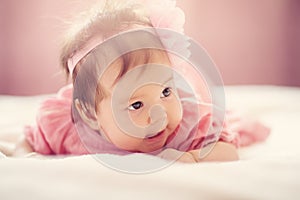 Cute little baby girl lying in the bed in pink dress