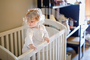 Cute Little Baby Girl Lying in Cot after Sleeping. Healthy Happy Child in Bed Climbing Out. Danger for Babies and