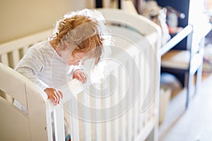 Cute Little Baby Girl Lying in Cot after Sleeping. Healthy Happy Child in Bed Climbing Out. Danger for Babies and