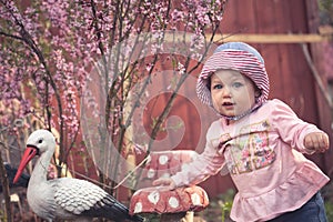 Cute little baby girl in pink dress possing for camera in the park