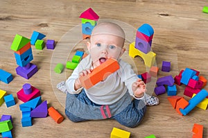 Cute little baby girl playing with colorful toy blocks