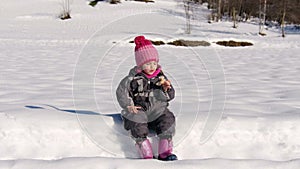 Cute little baby girl in snowsuit have snack taking break on snowshoeing hike in snow winter countryside