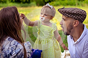 Cute little baby girl touches her mothers nose at the family picnic at the park