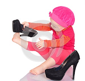 Cute little baby girl trying on her mother's shoes on white back