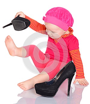 Cute little baby girl trying on her mother's shoes on white back