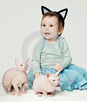 Cute little baby girl with two hairless kittens