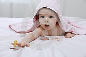 Cute little baby in hooded towel after bathing on bed at home