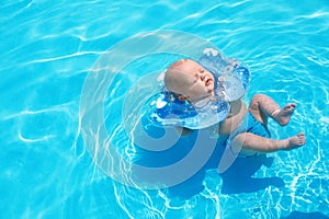 Cute little baby with inflatable neck ring in swimming pool