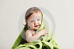 Cute little baby leaning out of cozy green blanket.