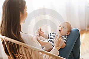 Cute little baby lying on mother`s lap and cooing