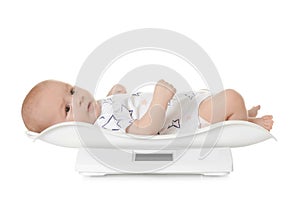 Cute little baby lying on scales against white