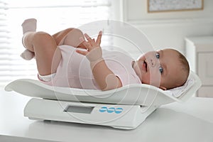 Cute little baby lying on scales at home