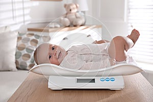 Cute little baby lying on scales at home