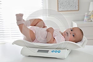 Cute little baby lying on scales at home