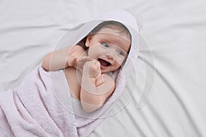 Cute little baby with pacifier in hooded towel after bathing on bed, top view