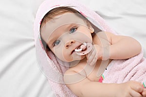 Cute little baby with pacifier in hooded towel after bathing on bed, top view