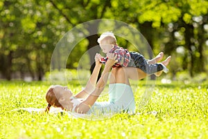 Cute little baby in the park with mother on the grass. Sweet baby and mom outdoors. Smiling emotional kid with mum on a walk. Sm