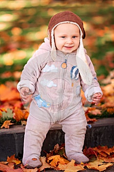 Cute little baby playing in autumn leaves